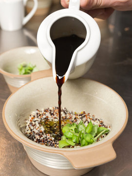 Balsamic vinegar being poured into a rustic bowl of Organic quinoa