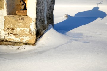 This country chapel cross casting a shadow on snow