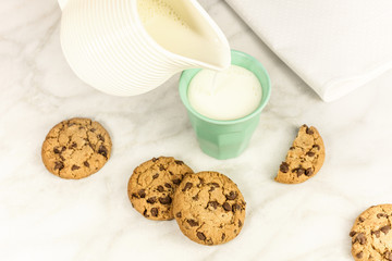 Milk poured into glass, with chocolate chips cookies