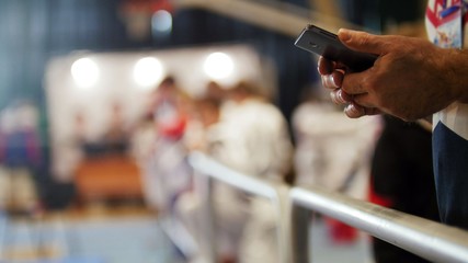 Man uses smartphone at sport competitions of karate