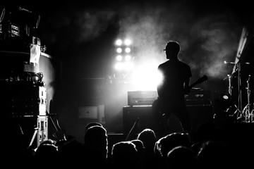 silhouette of guitar player in action on concert stage, black and white