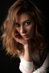 close up studio portrait of young serious woman in white blouse on black background