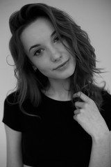 Portrait of a young girl in a black T-shirt looking at the camera . Black and white vertical photo