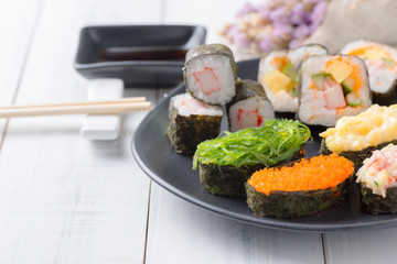 seaweed sushi on black dish and white wood background