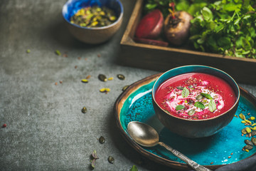 Spring detox beetroot soup with mint, chia, flax and pumpkin seeds in blue ceramic bowl over grey...