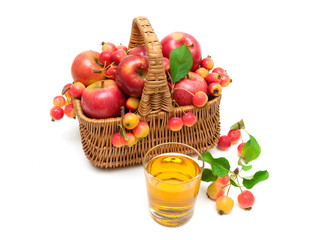 apples in a wicker basket and a glass of juice isolated on white background