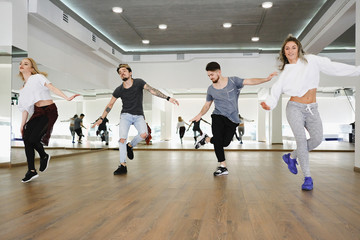 Group of young modern dancers dancing in the studio. Sport, dancing and urban culture concept - obrazy, fototapety, plakaty