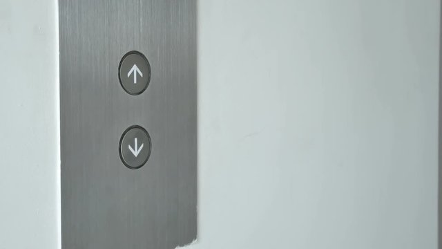 Elevator button press with an orange down arrow, close-up on finger