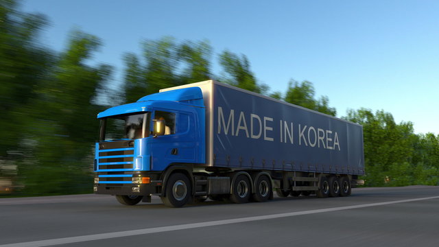 Speeding freight semi truck with MADE IN KOREA caption on the trailer. Road cargo transportation. 3D rendering