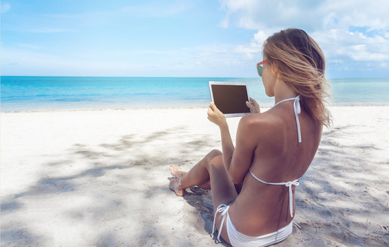 Happy young woman with a tablet in a tropical paradise resort. Communication during the holidays