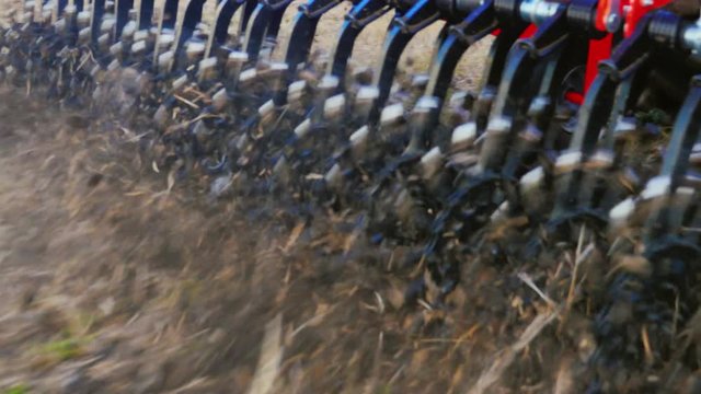 Steadicam tracking shot: A close-up of a part of an agricultural machine is a rotating cultivator. Handles the ground to remove weeds and prevent the drying of the soil