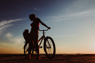 Fototapeta premium Silhouette of mother and baby biking at sunset