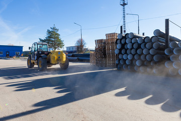 Kohonovo, Belarus - 29 October 2015: tractor loads stacks of black pvc plastic pipe outdoors outside the warehouse