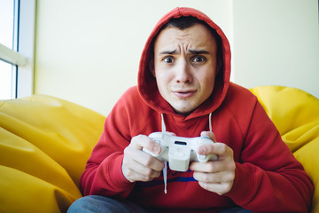 Emotional teenager playing home games console using a gamepad. Video games in his spare time....