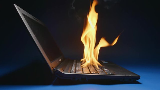 SLOW MOTION: Laptop flaming on a table - Side view