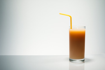 Banana juice in a glass and a tube for a cocktail, on a light gradient background is highlighted with space for text