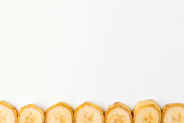 Background of sliced banana slices from below into a row on a white table with space for text