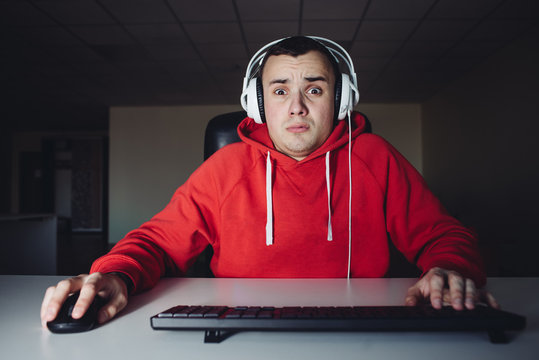 The young man plays a home game on his computer. Gamer fear looking at your computer monitor