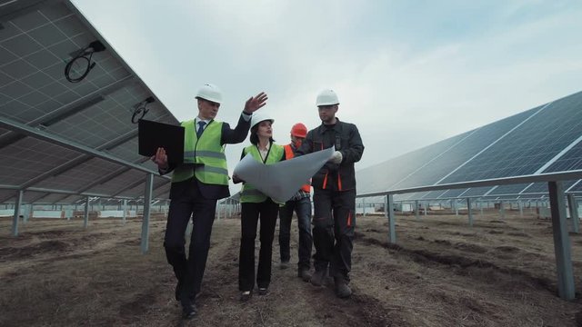 The engineers walking in the solar energy panels and discussing the blueprint.