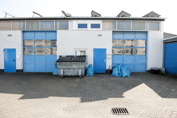 Gewerbehof mit blauen Toren und Müllcontainer