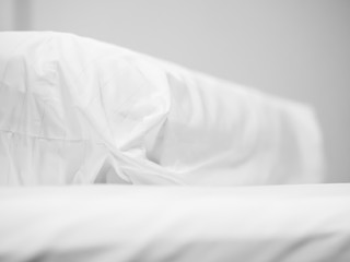 Closeup of white bolster on bed in bedroom.