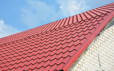 Building new house with metal red roof, roofing construction outdoor.
