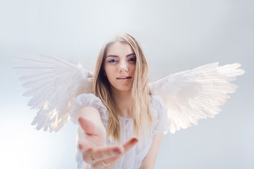 An angel from heaven gives you a hand. Young, wonderful blonde girl in the image of an angel with...
