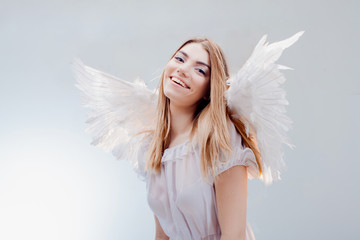 An angel from heaven. Young, wonderful blonde girl in the image of an angel with white wings.