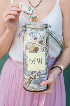 Woman Putting Money Into The Bottle With Savings For The Future Dream