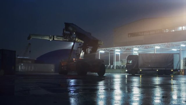 At Night Reach Stacker Driving in Working Area near Industrial Warehoses. Shot on RED EPIC-W 8K Helium Cinema Camera.