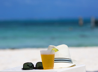 Cold beer on the beach. White table along with sunglasses and a summer hat. Relaxing vacation concept image. 