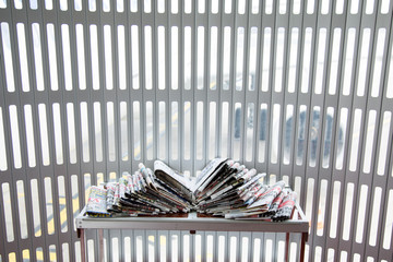 Stack of daily newspapers in the airport in Paris, France. Medias and communication concept. Pile of colorful newspapers for traveling people.
