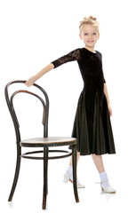 Fototapeta premium Slender little dancer posing near the old Vienna chair.