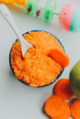 Baby food carrot puree with green apples in ceramic bowl on white background
