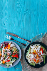 salad and pasta with seafood on a blue wooden background