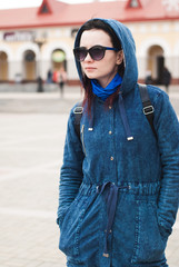 Young woman standing on the street blurred the background of the building and looks, Street style,