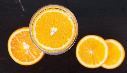 Orange slice in the glass, the view from the top, on a black wooden background, closeup,