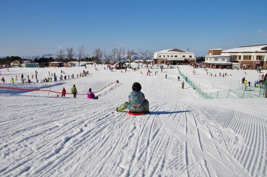 日本のスキー場でそりで遊ぶ子供