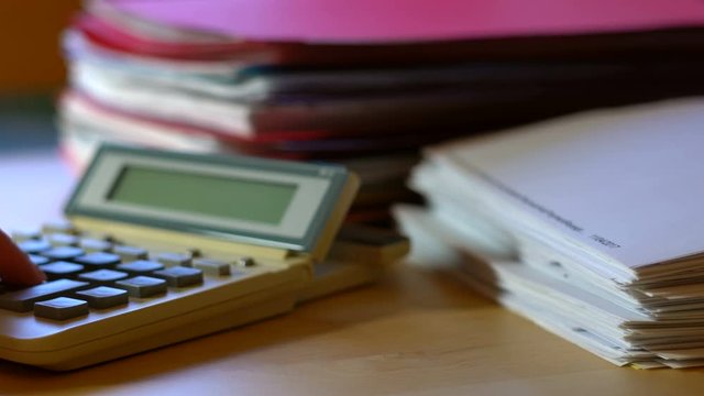 Calculator macro closeup with stacks of invoices, paperwork, and files