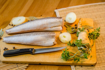 Fish fillet with onion and parsley on wooden tray background