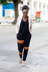 Pretty African woman hands in pockets crosses the road looking at the camera.