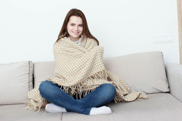 Obraz premium girl is sitting on the sofa under the rug.