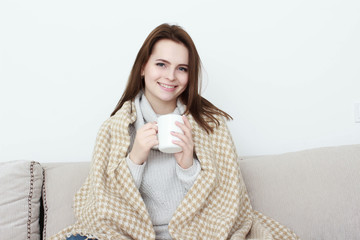 Girl sitting on sofa in livingroom with cup of tea