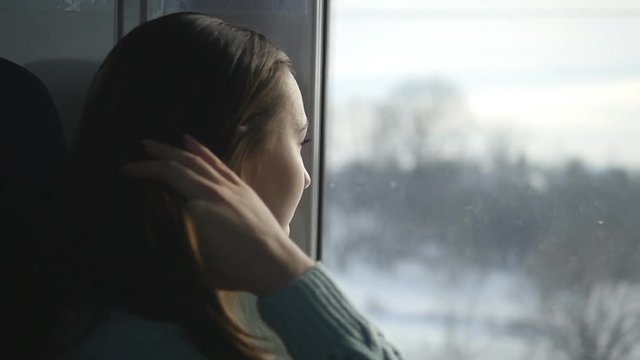 Young woman looking on window during riding on train. Profile of attractive girl traveling on railroad. Slow motion
