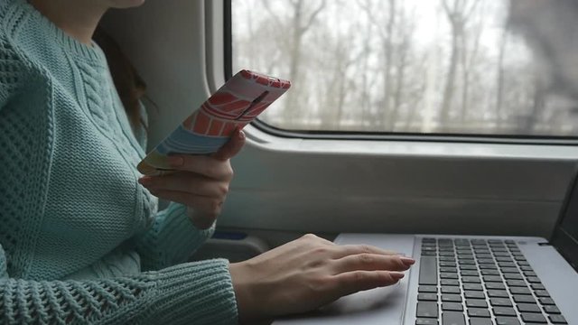 Female hands using touchpad of laptop pc and smartphone in train. Arm of young woman touching touchscreen of notebook during traveling on railroad. close up. Slow motion