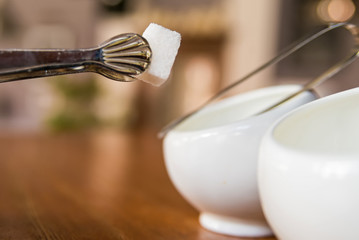 Sugar cubes in sugar bowl and sugar tongs