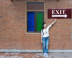 Obraz na płótnie Canvas Asian women Stand against the brick wall The hand points to the exit sign.