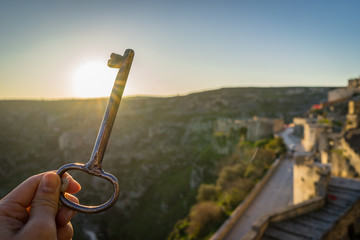 travel concept with woman hand holding a vintage hotel key, morning sunrise meadow