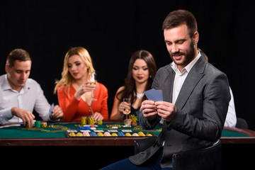 Poker players in casino with cards and chips on black background