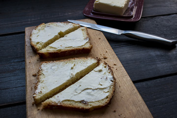 Homemade sahdwiches with butter and knife on a wooden table .
